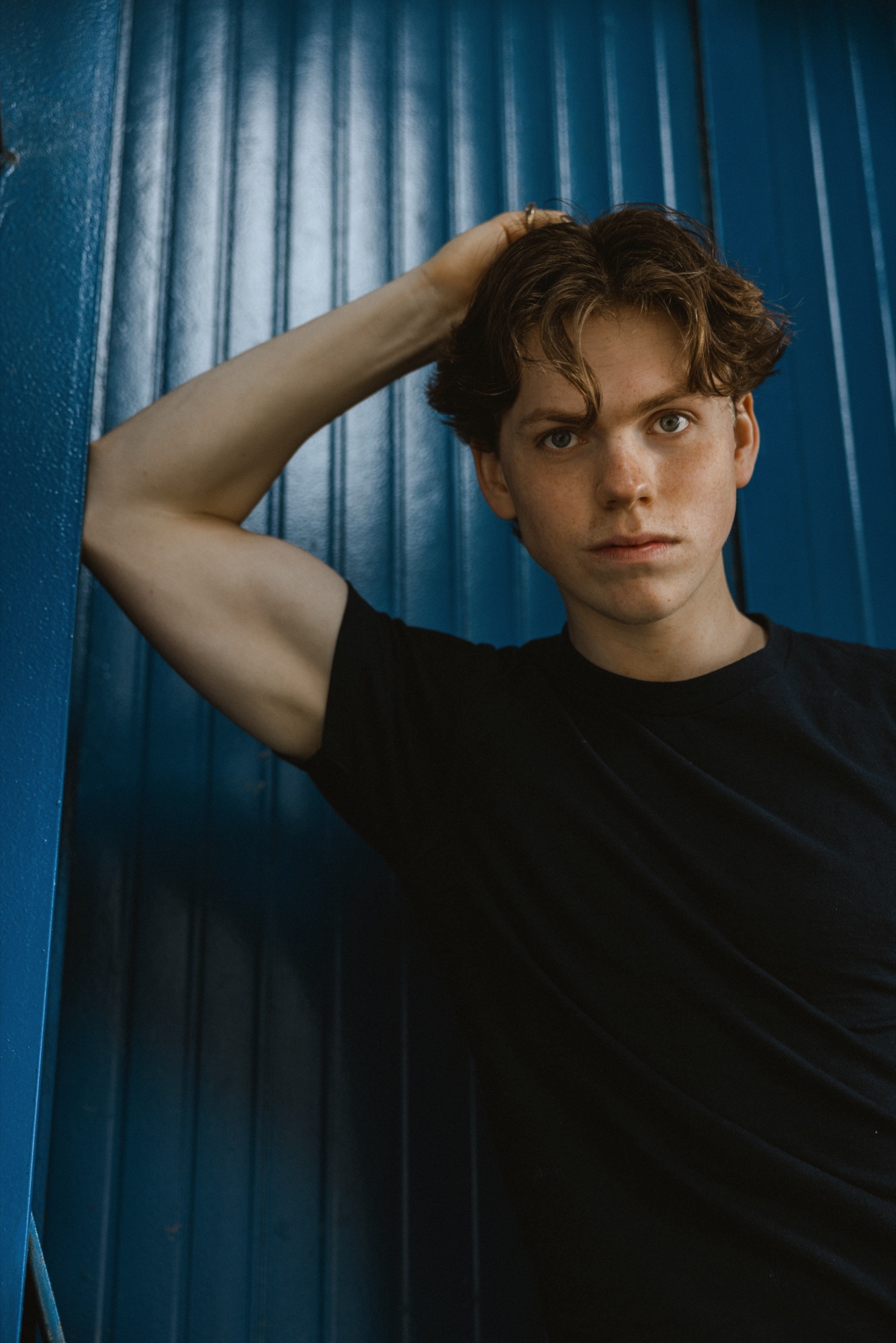 Senne met een hand in zijn haar tegen een blauwe wand